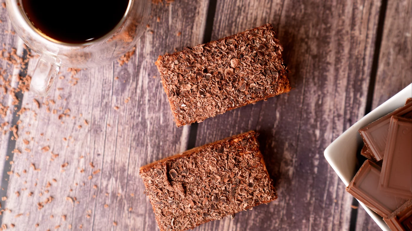 Mikado slice. Two rectangular brown cake slices with rough dark crumb-like tops, photographed from above on a wooden table.