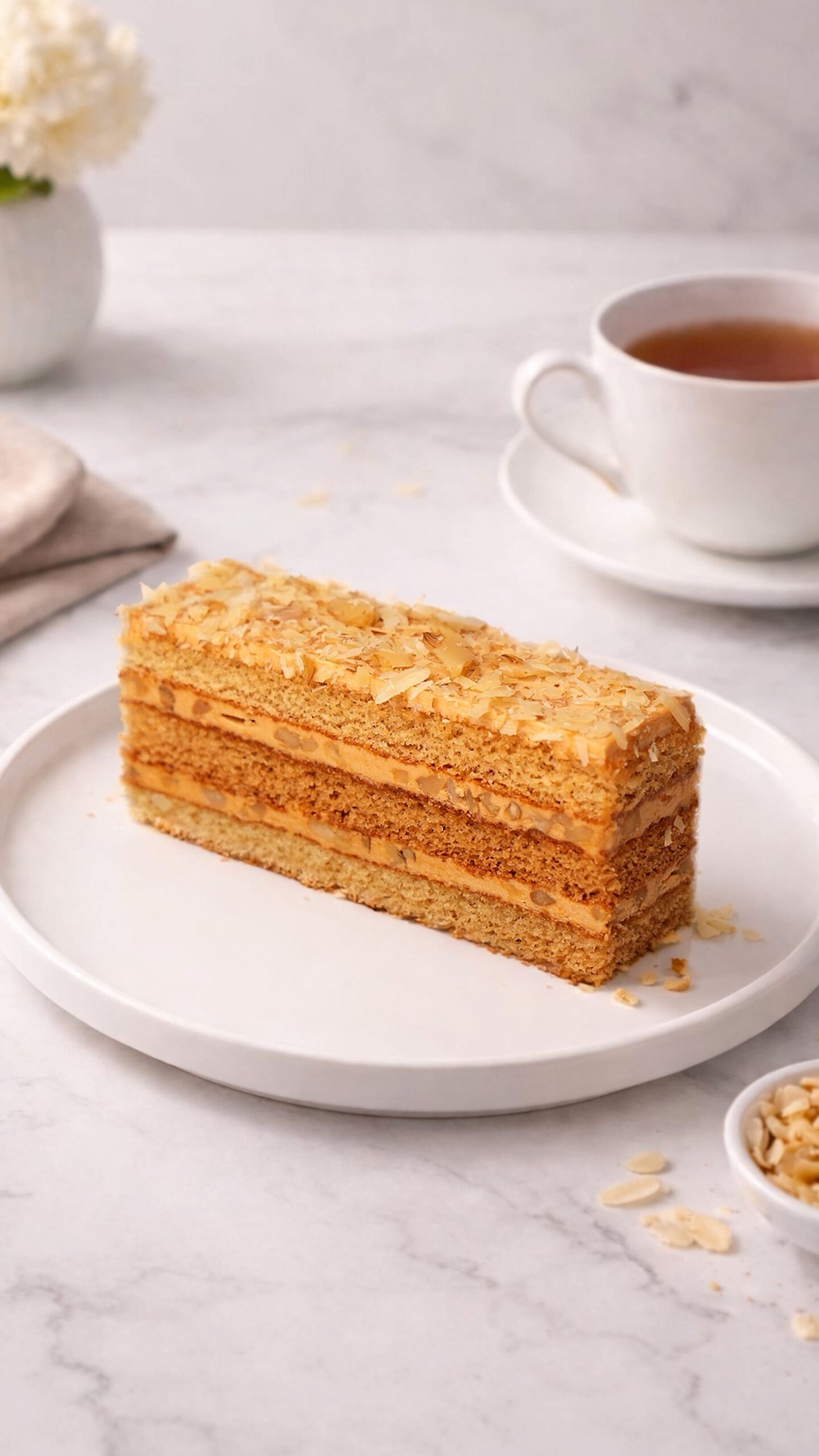 Ideal slice. Rectangular golden cake slice with many thin horizontal layers and a textured golden topping, served on a white plate.