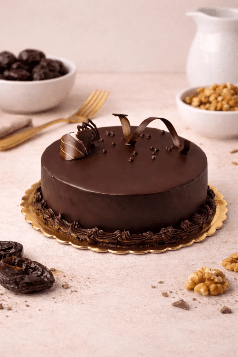 Plum nut cake. Round cake with a smooth dark brown coating, curled dark decorations on top, and a dark piped base border.